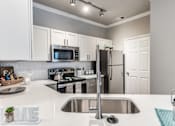 Thumbnail 16 of 36 - A kitchen with a stove, sink, and refrigerator at Rosemary Apartments, Texas