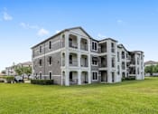 Thumbnail 14 of 36 - A large, grey apartment building with multiple balconies and doors at Rosemary Apartments, Conroe, TX