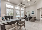 Thumbnail 21 of 36 - A well-lit office with a desk, chairs, and a ceiling fan at Rosemary Apartments, Conroe