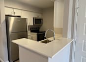 Thumbnail 14 of 17 - A kitchen with a stainless steel refrigerator and a white countertop.