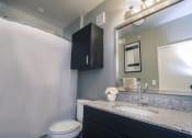 Thumbnail 19 of 37 - a bathroom with a white toilet next to a sink with a mirror and a shower curtain at Republic at Alamo Heights, Texas, 78209