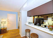 Thumbnail 12 of 16 - A kitchen area with a bar stool and a counter with a coffee maker.