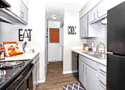 Thumbnail 13 of 16 - A kitchen with a black refrigerator and a white counter top.
