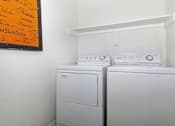 Thumbnail 10 of 16 - a washer and dryer in a white room with a sign on the wall