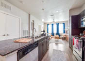 Thumbnail 9 of 27 - a kitchen with a large island and a living room in the background at The Landings at Brooks City-Base, San Antonio, TX, 78235