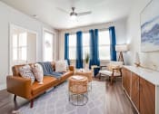 Thumbnail 8 of 27 - a living room with a brown couch and blue curtains at The Landings at Brooks City-Base, San Antonio, 78235