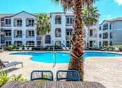 Thumbnail 27 of 36 - A palm tree stands in front of a pool at a resort at Rosemary Apartments, Texas, 77384