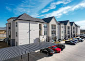 Thumbnail 4 of 25 - a row of apartment buildings with cars parked in front of them at The Fitzroy San Marcos, Texas