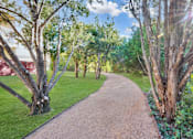 Thumbnail 11 of 72 - a gravel path through a grassy area with trees on either side at Radius on Grove, Austin, TX, 78741