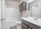 Thumbnail 9 of 35 - Modern bathroom with vanity and tub at Houston Street Townhomes Apartments, San Antonio