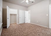 Thumbnail 10 of 35 - Empty bedroom with beige carpet and closet at Houston Street Townhomes Apartments, San Antonio, TX 78220