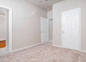 Thumbnail 29 of 35 - Empty room with carpet and two white doors at Houston Street Townhomes Apartments, San Antonio, 78220