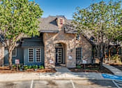 Thumbnail 19 of 35 - Brick and stone clubhouse exterior with arched entry at Houston Street Townhomes Apartments, Texas, 78220