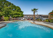 Thumbnail 23 of 35 - Resort style pool with palm tree and fencing at Houston Street Townhomes Apartments, San Antonio, TX 78220