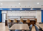 Thumbnail 1 of 18 - A modern kitchen with a long table and chairs.at Mainline North Apartments - Santa Clara, CA, California