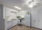 Thumbnail 10 of 11 - A white kitchen with a fan on the ceiling.