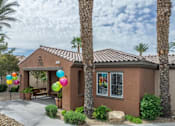 Thumbnail 9 of 11 - A house with a brown roof and tan walls is surrounded by palm trees and has balloons tied to the front door.