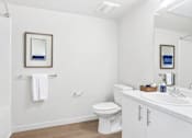 Thumbnail 5 of 12 - A white bathroom with a toilet, sink, and mirror.
