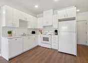 Thumbnail 11 of 18 - A white kitchen with wooden floors and white appliances.at Mainline North Apartments - Santa Clara, CA, Santa Clara, CA