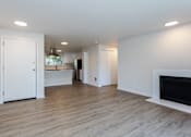 Thumbnail 2 of 20 - A white interior with a fireplace and a kitchen in the background.