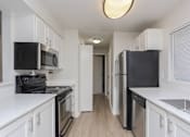 Thumbnail 3 of 20 - A kitchen with black appliances and white cabinets.