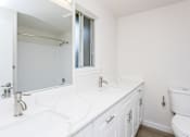 Thumbnail 13 of 20 - A white bathroom with a toilet, sink, and mirror.