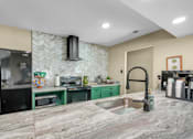 Thumbnail 3 of 19 - A kitchen with a marble countertop and green cabinets.