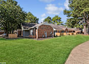 Thumbnail 12 of 19 - a small brick house with a yard and trees at The Birches Apartment Homes, Memphis, TN