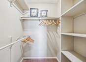 Thumbnail 12 of 24 - A white closet with a hanger and two clocks on the shelf.