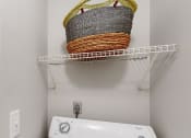 Thumbnail 24 of 46 - a washer and dryer in a laundry room with a basket on the wall at Island Club Apartments, Columbus, 43235