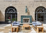 Thumbnail 16 of 26 - A fireplace with a wooden mantle and two couches in front of a building with arched windows.