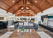 Thumbnail 1 of 24 - A modern living room with a wooden ceiling and a black leather couch.