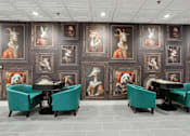 Thumbnail 22 of 26 - A room with a table surrounded by chairs and pictures of animals on the wall.