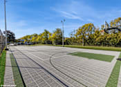 Thumbnail 27 of 46 - A basketball court with a green and grey surface and a basketball hoop on the right side. at Island Club Apartments, Columbus