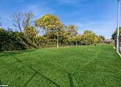 Thumbnail 28 of 46 - A grassy field with trees in the background and a fence on the right side at Island Club Apartments, Ohio
