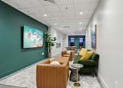 Thumbnail 20 of 26 - A long hallway with a green couch and a painting on the wall.