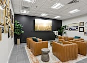 Thumbnail 25 of 26 - A room with orange couches and a large painting on the wall.