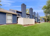 Thumbnail 14 of 24 - a row of blue houses with a yard and green grass at The Vale Apartments and Townhomes, Cordova, TN