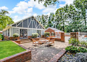 Thumbnail 13 of 19 - A modern house with a grey and white exterior and a red brick wall.