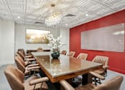 Thumbnail 10 of 26 - A long wooden table is surrounded by chairs in a room with a chandelier hanging from the ceiling.