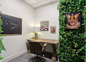 Thumbnail 14 of 26 - A room with a desk, chair, and a green plant wall.