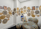 Thumbnail 13 of 26 - A chair with a black and gold striped cover sits in front of a wall with circular and leaf shaped decorations.