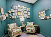 Thumbnail 11 of 26 - A room with two chairs and a table with a lamp on it.