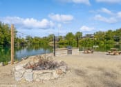 Thumbnail 20 of 35 - a fire pit next to a lake with picnic tables at Runaway Bay Apartments, Ohio