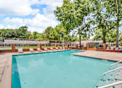 Thumbnail 14 of 19 - A large outdoor swimming pool surrounded by trees and lounge chairs.