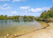 Thumbnail 16 of 35 - a lake with a sandy beach and trees at Runaway Bay Apartments, Columbus, OH, 43204