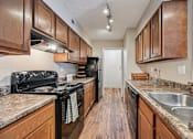 Thumbnail 7 of 24 - A kitchen with wooden cabinets and a black stove top oven.