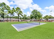 Thumbnail 17 of 19 - A tennis court surrounded by trees and a fence.