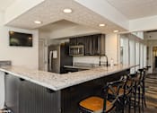 Thumbnail 45 of 46 - A kitchen with a bar area and a television mounted on the wall. at Island Club Apartments, Columbus, OH