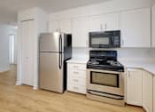 Thumbnail 14 of 20 - A kitchen with a refrigerator, oven, and microwave.